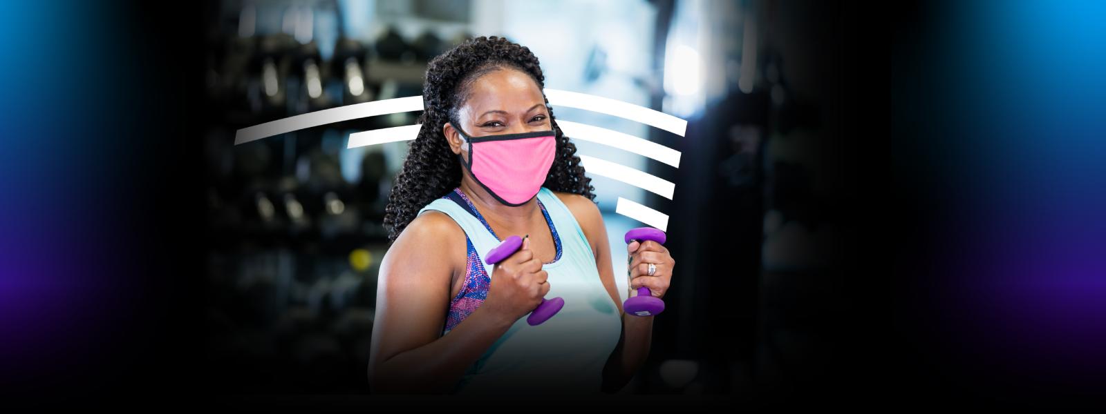 Woman wearing a mask holding dumbbells 